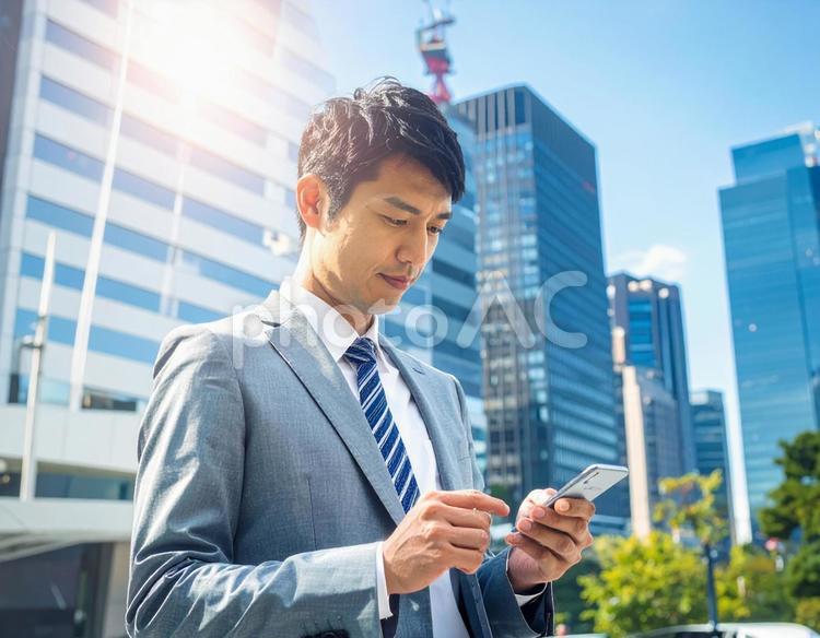 オフィス街でスマホを操作する男性社員 スマホ,ビジネス,操作の写真素材