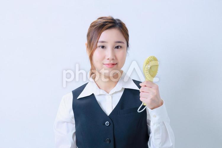 ハンディファンで涼むカメラ目線のOL 女性,日本人,若いの写真素材
