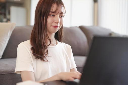 リビングでパソコンを操作する女性 リビングでパソコンを操作する女性 フリーランス,プログラミング,プログラマーの写真素材