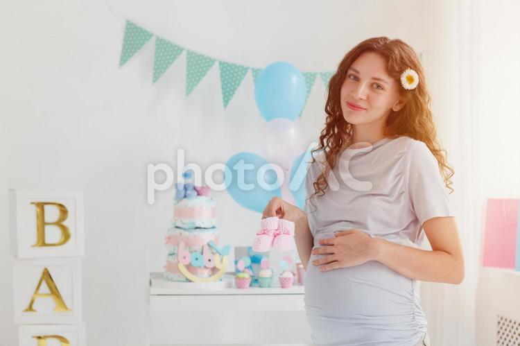 ベビーシューズを持っている妊婦と日差し 女性,人物,風船の写真素材