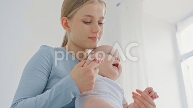 赤ちゃんが握った指を見つめる女性 親子,抱っこ,見るの写真素材