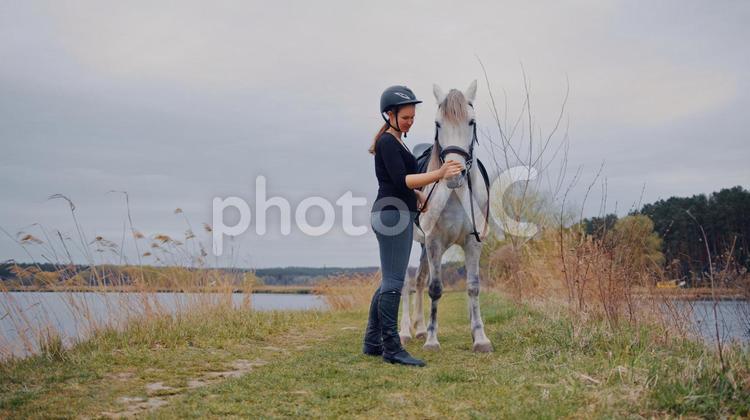 湖畔を散歩する白馬と騎手 馬,斜め,全身の写真素材