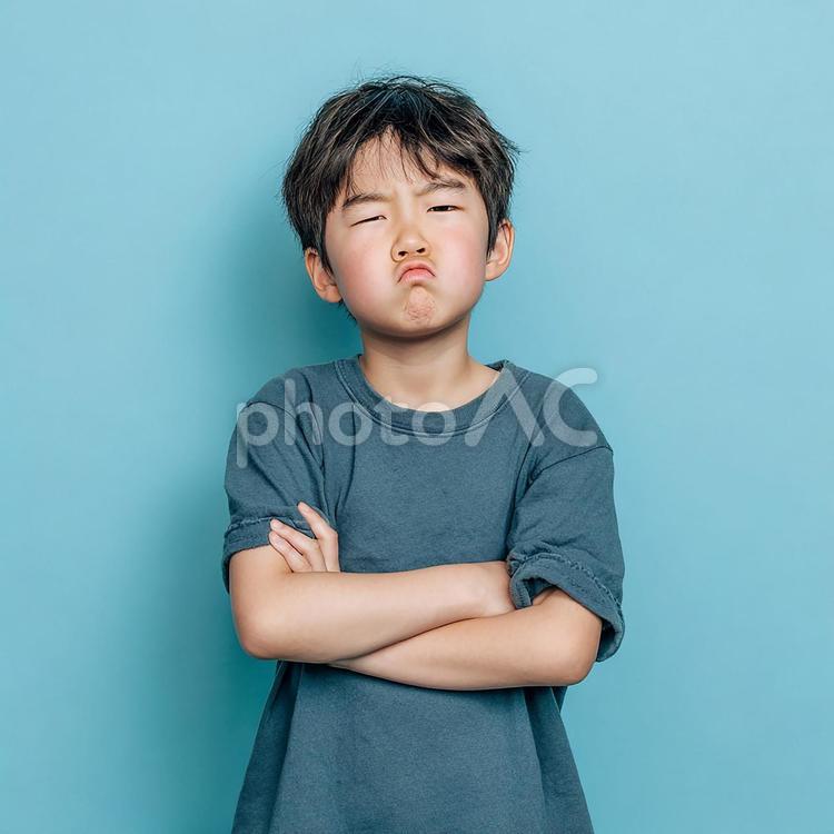 青い背景をバックに、困惑した様子の男の子 男の子,子供,小学生の写真素材