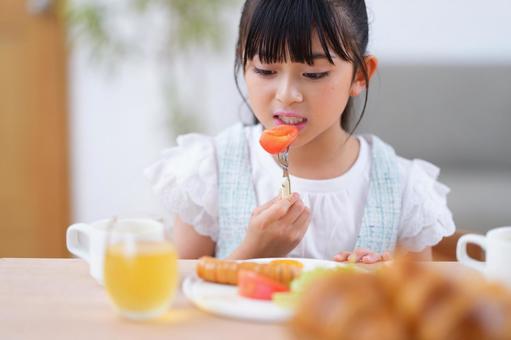 朝食のトマトをフォークで食べる女の子の写真