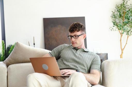 ソファで膝の上でノートパソコンを使う男性 男性,外国人,欧米人の写真素材