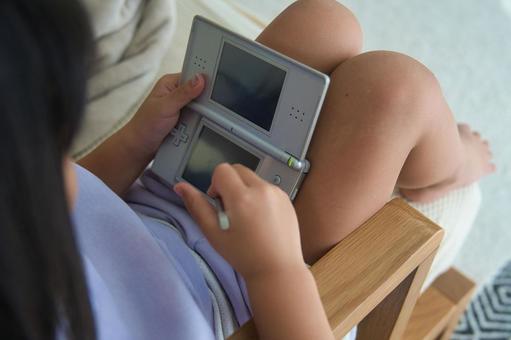 携帯ゲーム機で遊ぶ女の子 携帯ゲーム機で遊ぶ女の子の写真