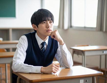 教室で1人で悩む男子学生 教室で1人で悩む男子学生の写真