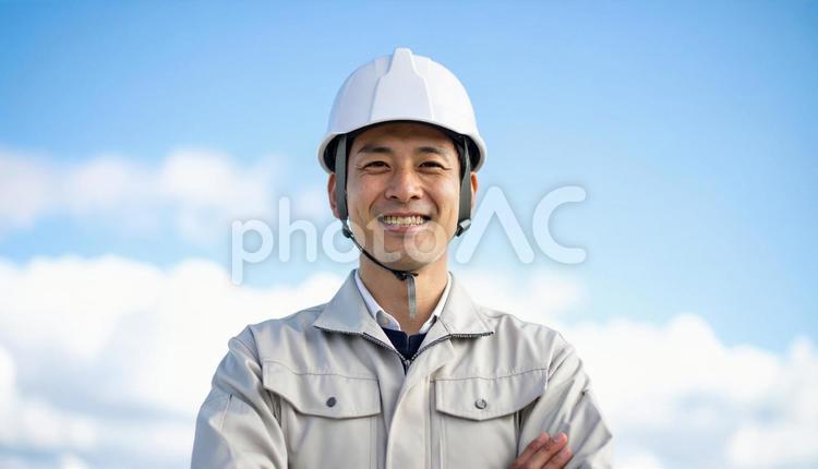 青空の下で笑顔の日本人若い男性建設作業員 作業服,男性,若いの写真素材