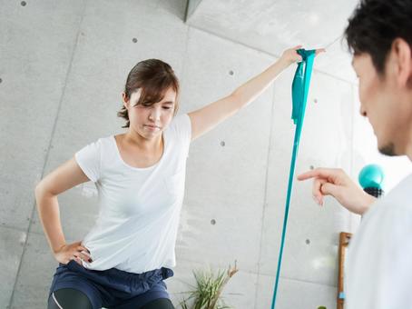 Japanese woman receiving tube training instruction from a personal trainer Japanese woman receiving tube training instruction from a personal trainer