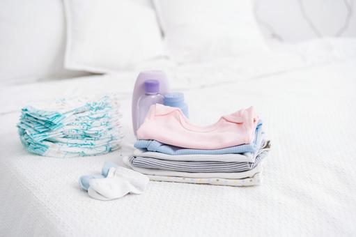 ベッドに置かれたベビー服やオムツ ベッドに置かれたベビー服やオムツ ベビー用品,人物無し,物撮りの写真素材