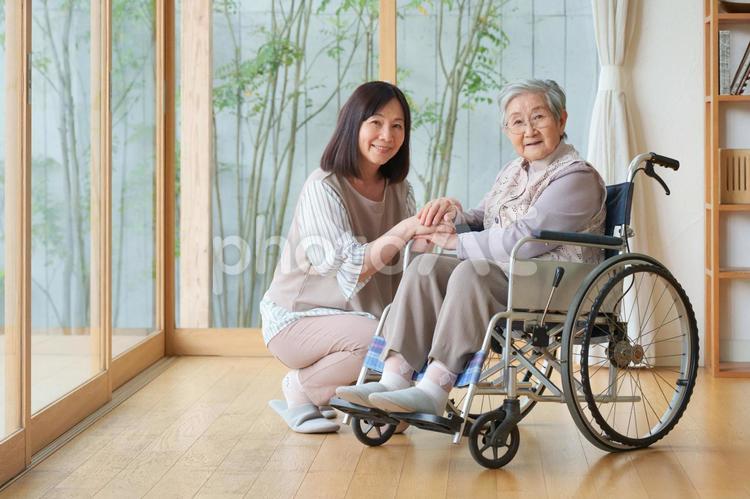 車椅子の女性と手を重ねる女性 女性,親子,手を重ねるの写真素材