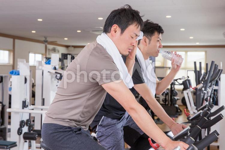 スポーツジムで自転車をこぐ男性 スポーツジム,男性,オーバーヒートの写真素材