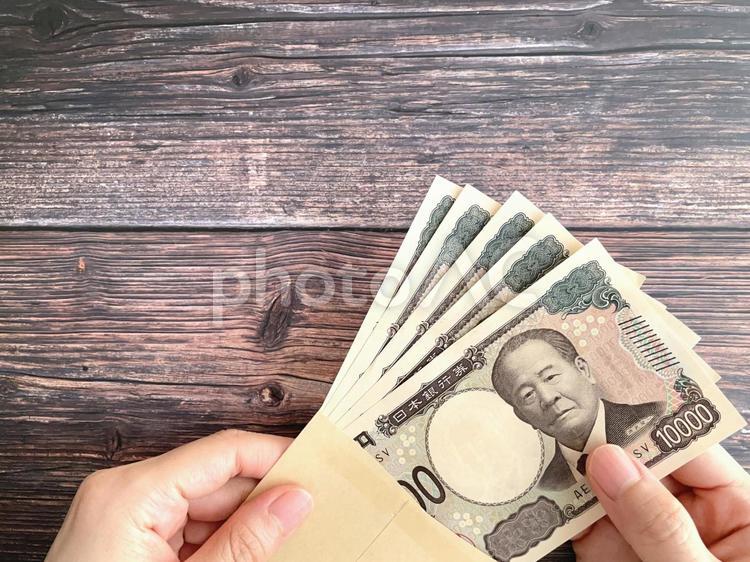 机上で封筒に入った5万円を持つ女性の手 5万円,お金,持つの写真素材