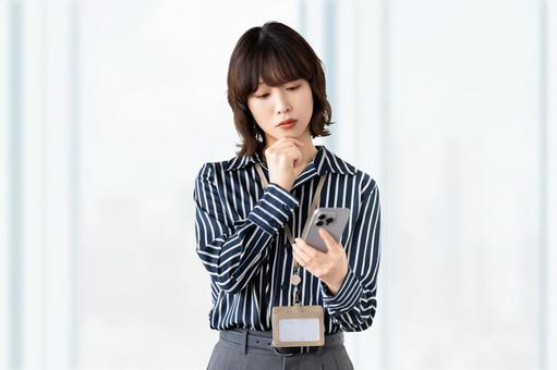 スマホを見て考える女性・ビジネスウーマン スマホを見て考える女性・ビジネスウーマン 女性,困る,考えるの写真素材