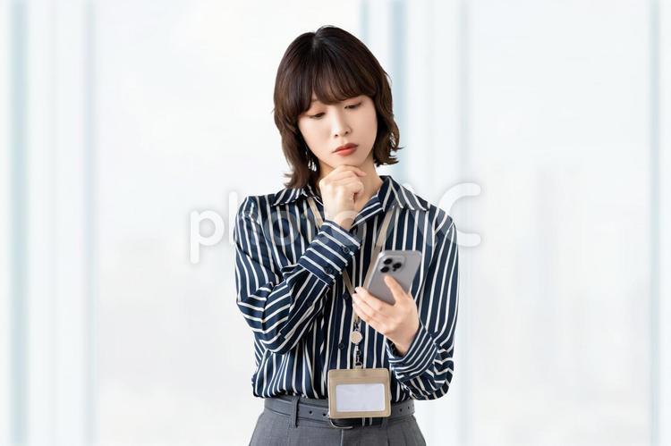 スマホを見て考える女性・ビジネスウーマン 女性,困る,考えるの写真素材