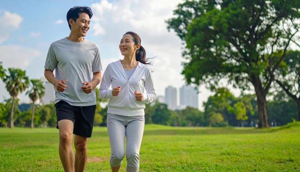 青空の見える公園をウォーキングする男女 青空の見える公園をウォーキングする男女の写真