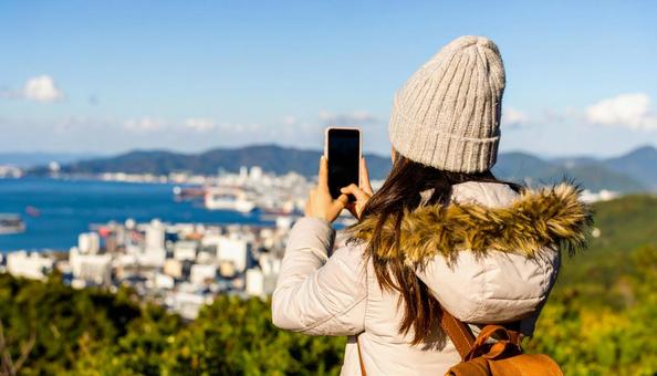 海の向こうを携帯で撮影する観光客の女性 海の向こうを携帯で撮影する観光客の女性の写真