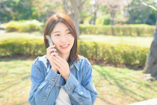 公園で電話をする女性 公園で電話をする女性の写真