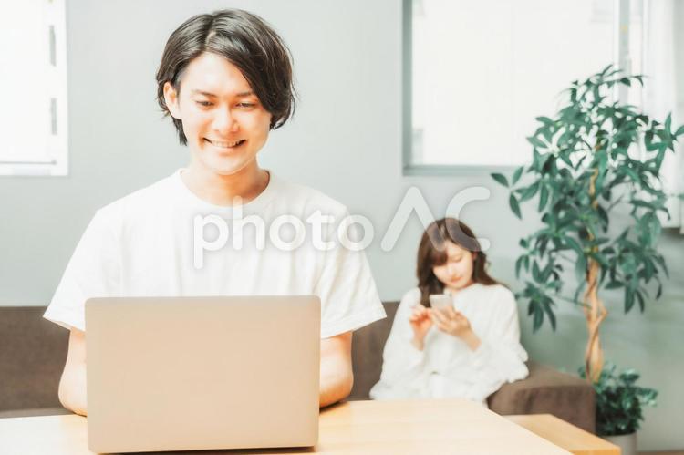 家でテレワークする男女（男性・笑顔） テレワーク,リモートワーク,ノートパソコンの写真素材