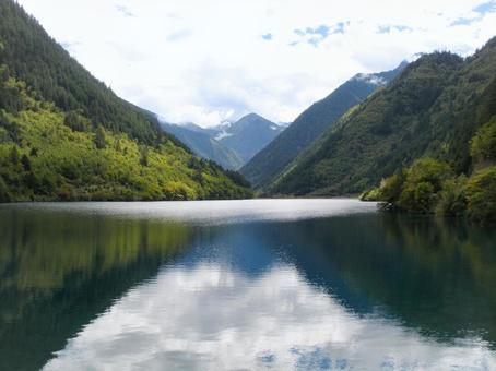 静かな湖に山並みと雲が映る美しい風景 静かな湖に山並みと雲が映る美しい風景の写真