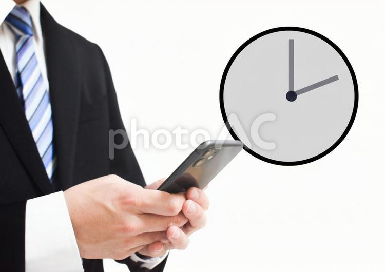 スマホ使うリクルートスーツの男性と時計 時計,時間,予定の写真素材