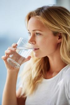 コップの水を飲む金髪の外国人女性 コップの水を飲む金髪の外国人女性の写真