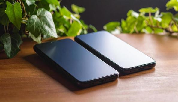 連絡交換のイメージ 机の上の携帯電話二台 連絡交換のイメージ 机の上の携帯電話二台の写真