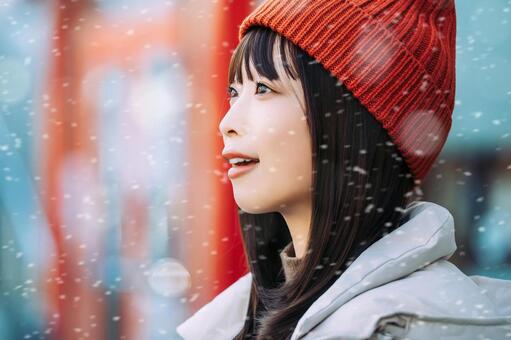 雪の降る冬の街角に立つ笑顔の女性 冬,雪,女性の写真素材