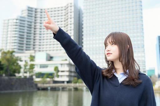 ビル街で大きく指をさす女子高生 ビル街で大きく指をさす女子高生 高校生,女子高生,指さしの写真素材