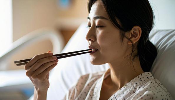 入院ベッドでご飯を食べる女性患者 入院ベッドでご飯を食べる女性患者の写真