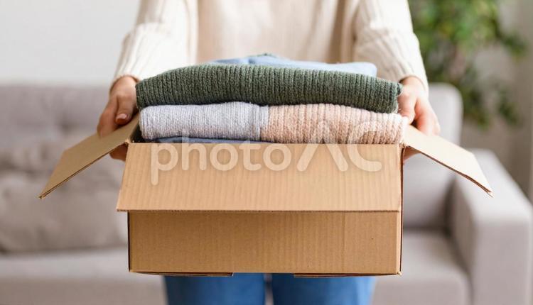 段ボールに古い衣類を詰めた女性の手 不用品,箱,女性の写真素材