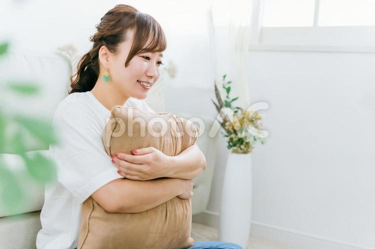 家でクッションを持つ笑顔のアジア人女性 女性,笑顔,笑うの写真素材