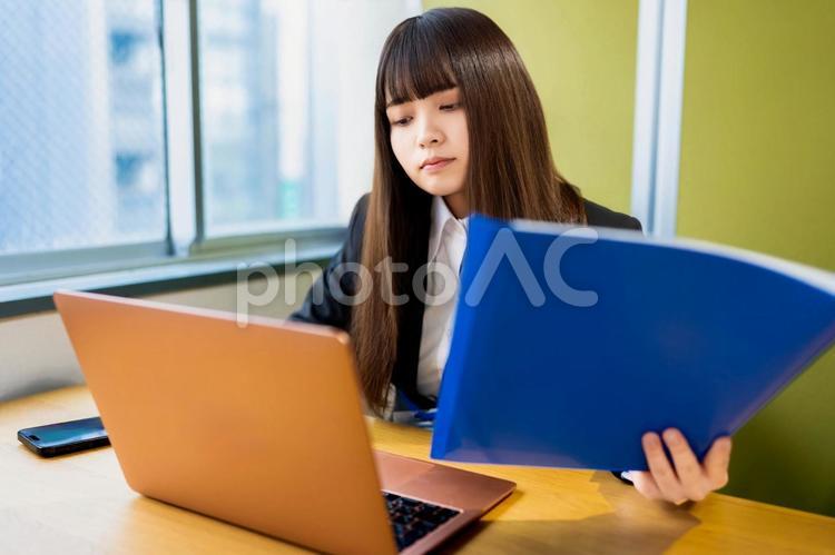 パソコンの前でファイルを持つ女性 女性,ビジネス,ビジネスウーマンの写真素材