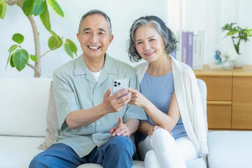 リビングでスマホを見るシニア夫婦 スマホ,シニア,笑顔の写真素材