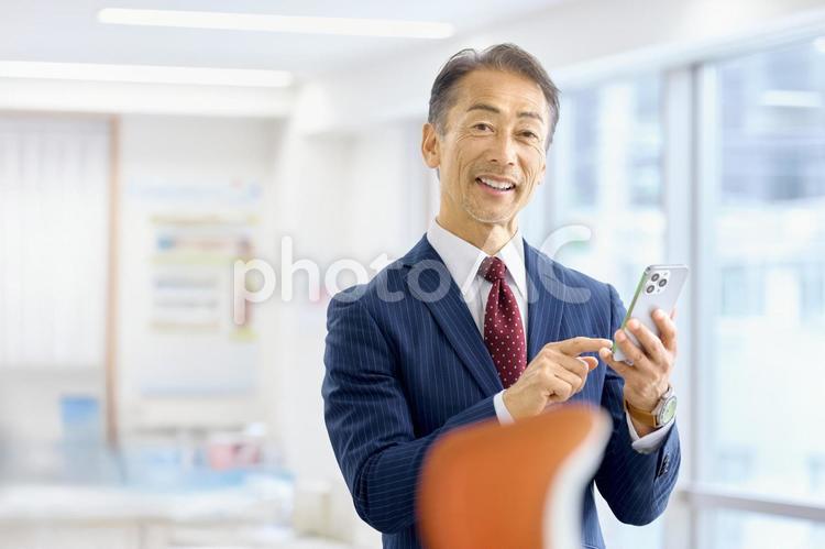 スマホを持つ中高年のビジネスマン　会社 ビジネスマン,経営者,中高年の写真素材