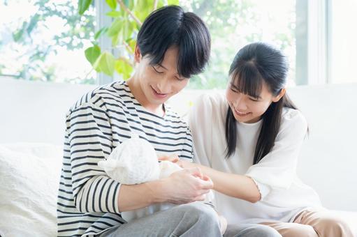 リビングで赤ちゃんを抱く若い家族 リビングで赤ちゃんを抱く若い家族 家族,親子,赤ちゃんの写真素材