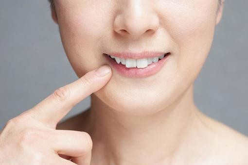 Middle-aged Japanese woman pointing at her mouth, bocca, dente, bocca, JPG