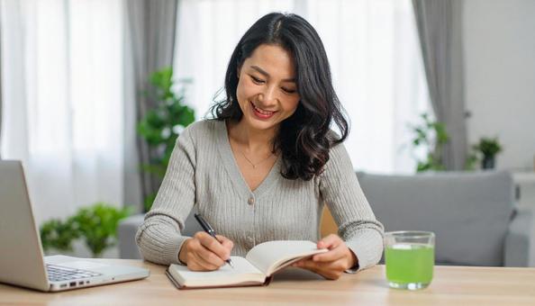 テキストを開きノートに書く日本人女性 テキストを開きノートに書く日本人女性の写真