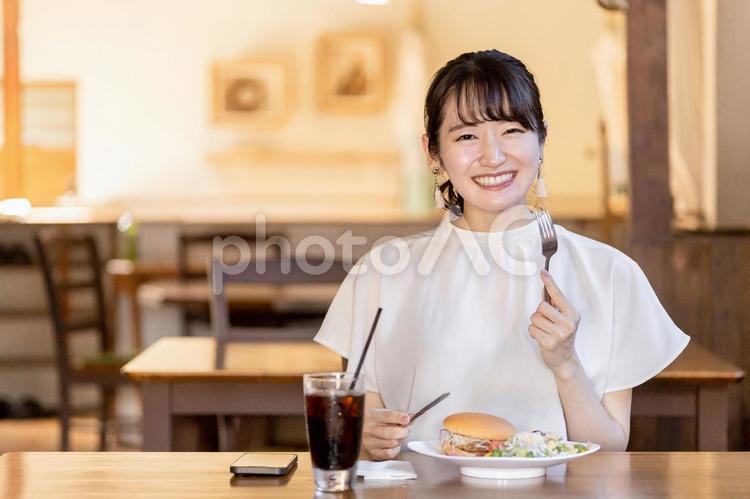 カフェで昼食にハンバーガーを食べる女性 ランチ,カフェ,ハンバーガーの写真素材