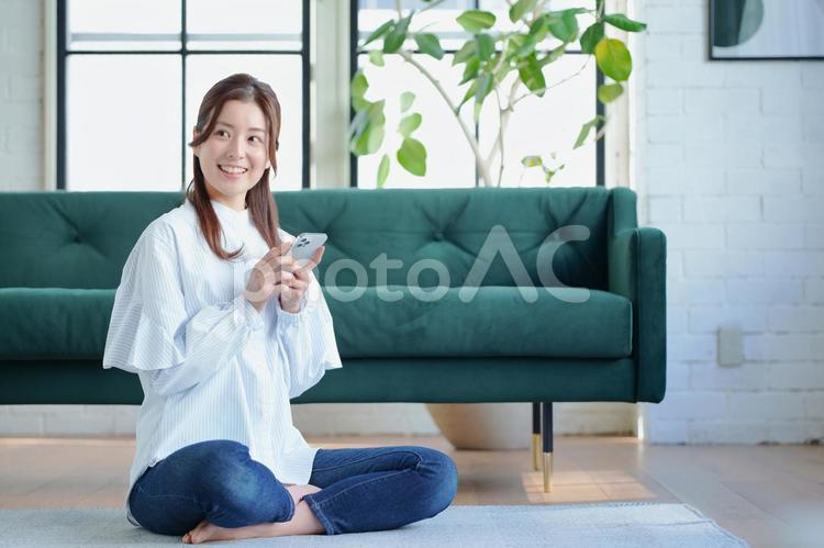 リビングの床でスマートフォンを使っている女性 女性,日本人,1人の写真素材