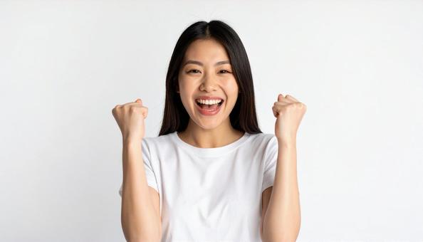 ガッツポーズで喜びを表す笑顔の若い女性の写真