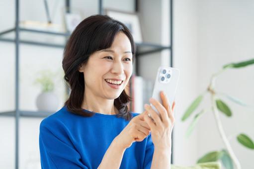 リビングでスマホを見るミドルの女性 リビングでスマホを見るミドルの女性 スマホ,女性,ミドルの写真素材
