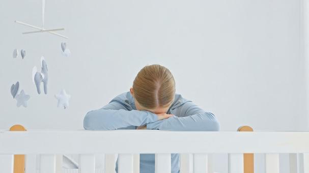 ベビーベッドの柵に顔を伏せる女性 ベビーベッドの柵に顔を伏せる女性 女性,ベビーベッド,育児疲れの写真素材