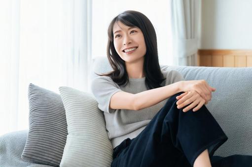 リビングのソファに座る笑顔の女性 リビングのソファに座る笑顔の女性 女性,ソファ,微笑むの写真素材