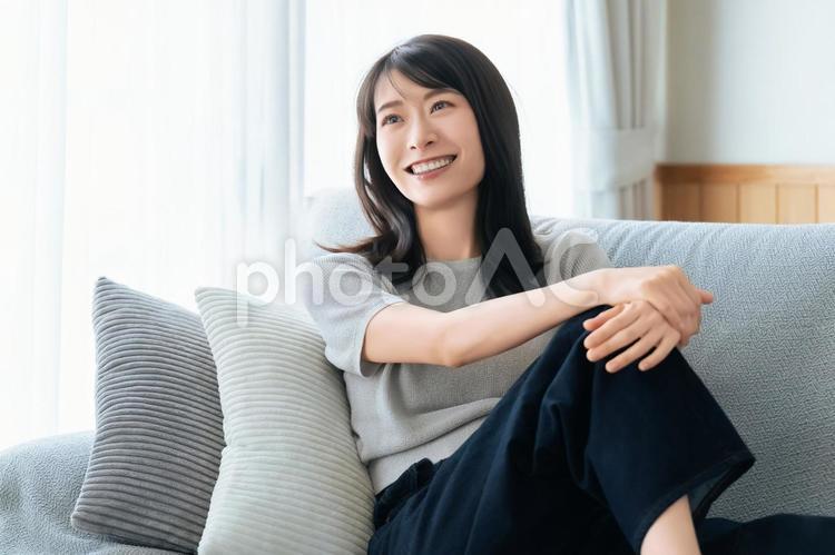 リビングのソファに座る笑顔の女性 女性,ソファ,微笑むの写真素材