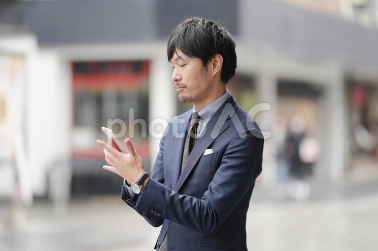 街中でスマホとビジネスマン ビジネス,スマホ,スマートフォンの写真素材