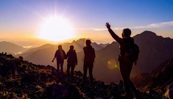 夏山で朝日に向かって手をあげる登山者 夏山で朝日に向かって手をあげる登山者の写真