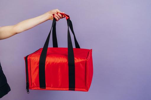 保温ピザバッグを持つ女性配達員の写真