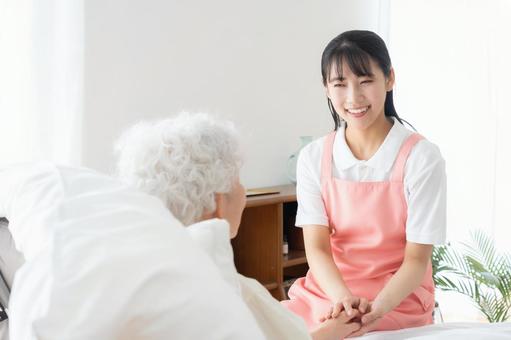 寝ているシニア女性を介護をする介護士 寝ているシニア女性を介護をする介護士 介護,介護士,シニアの写真素材