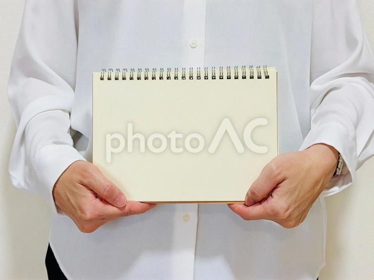白紙のノートを持つ女性（白シャツ） ノート,お知らせ,女性の写真素材